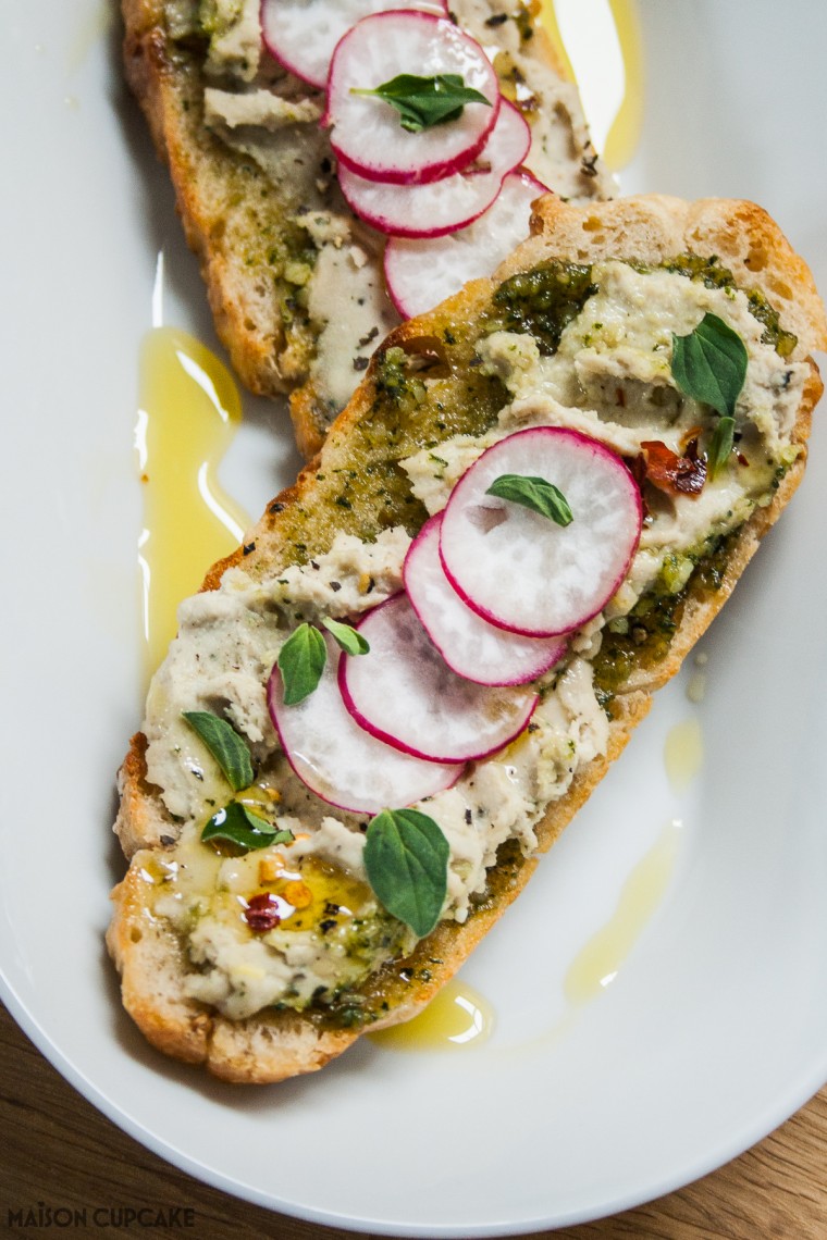 White bean hummus with homemade pesto on focaccia toast - easy to make with canned beans or dried pulses as a summer appetiser, vegetarian bean dip or sandwich filling