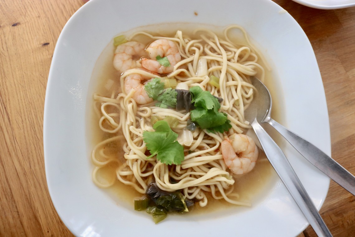 White bowl of tom yum prawn noodle soup recipe with fresh coriander garnish