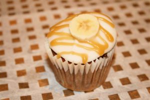 Banoffee Cupcake topped with cream cheese frosting, banana slice and toffee drizzle