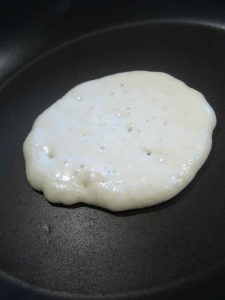 Blob of Scotch pancake batter frying on pan