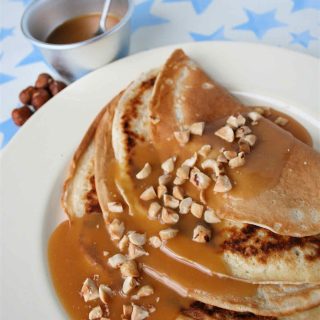 Folded pancakes covered with golden maple fudge sauce and chopped hazelnuts