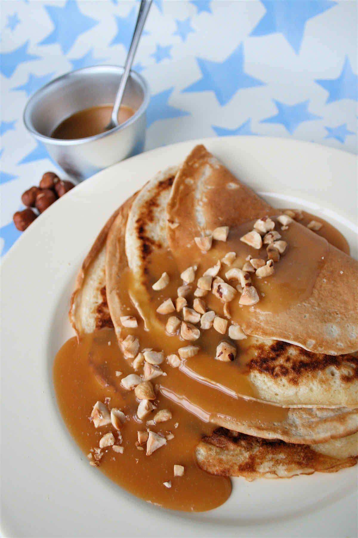 Folded pancakes covered with golden maple fudge sauce and chopped hazelnuts