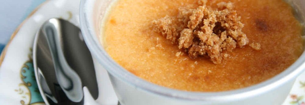 Lemon Custard Dessert with Cookie Crumbs: Silver ramekin of golden custard covered with biscuit crumbs; served on a vintage chintz plate with small serving spoon
