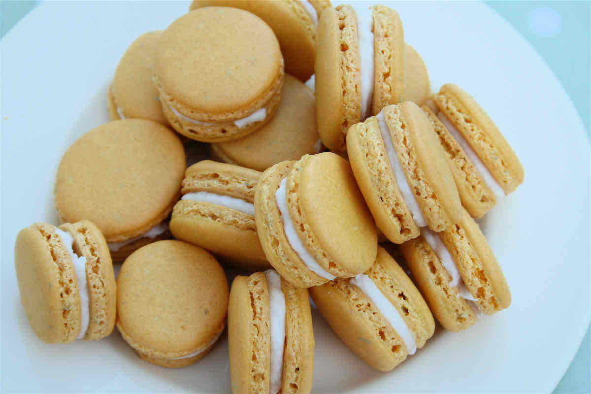 Lemon Macarons with Rosemary recipe - yellow macarons piled on a cream plate