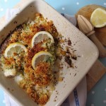 Baked fish with pesto covered with lemon slices.