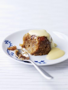 Sticky Toffee Pudding (Weight Watchers), a serving of golden brown pudding on a white plate with a spoon and custard