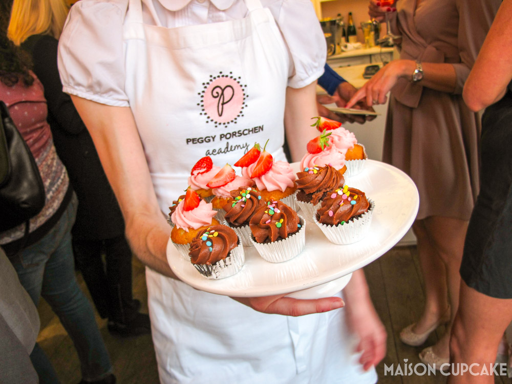 Peggy Porschen Boutique Baking Book Launch - staff member in branded apron holding tray of cupcakes