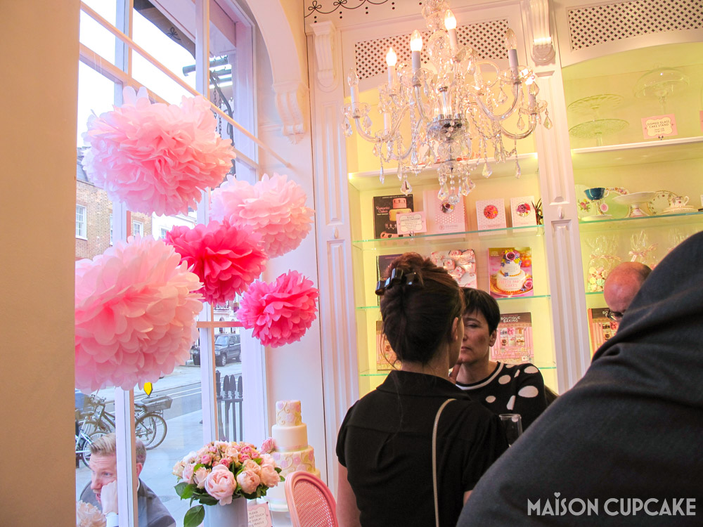 Peggy Porschen Parlour interior at Boutique Baking book launch with pink paper pom poms in window