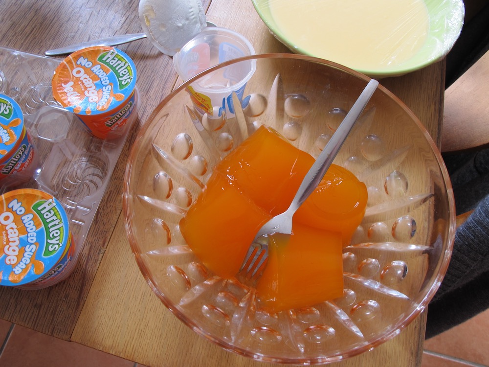 Ready made orange jellies in trifle dish with fork