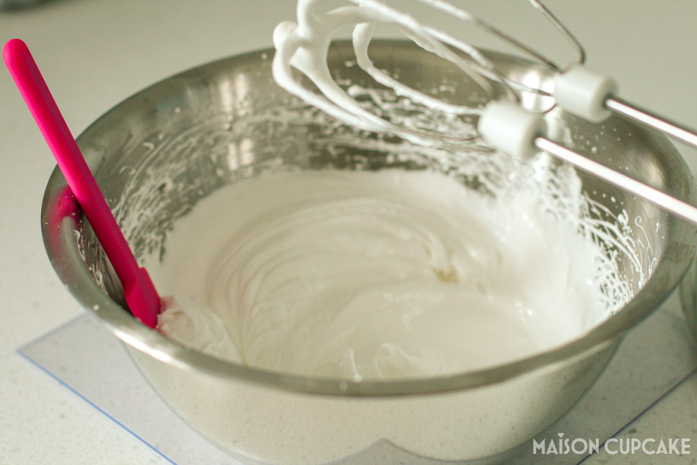 Egg whites whipped into meringue peaks in mixing bowl