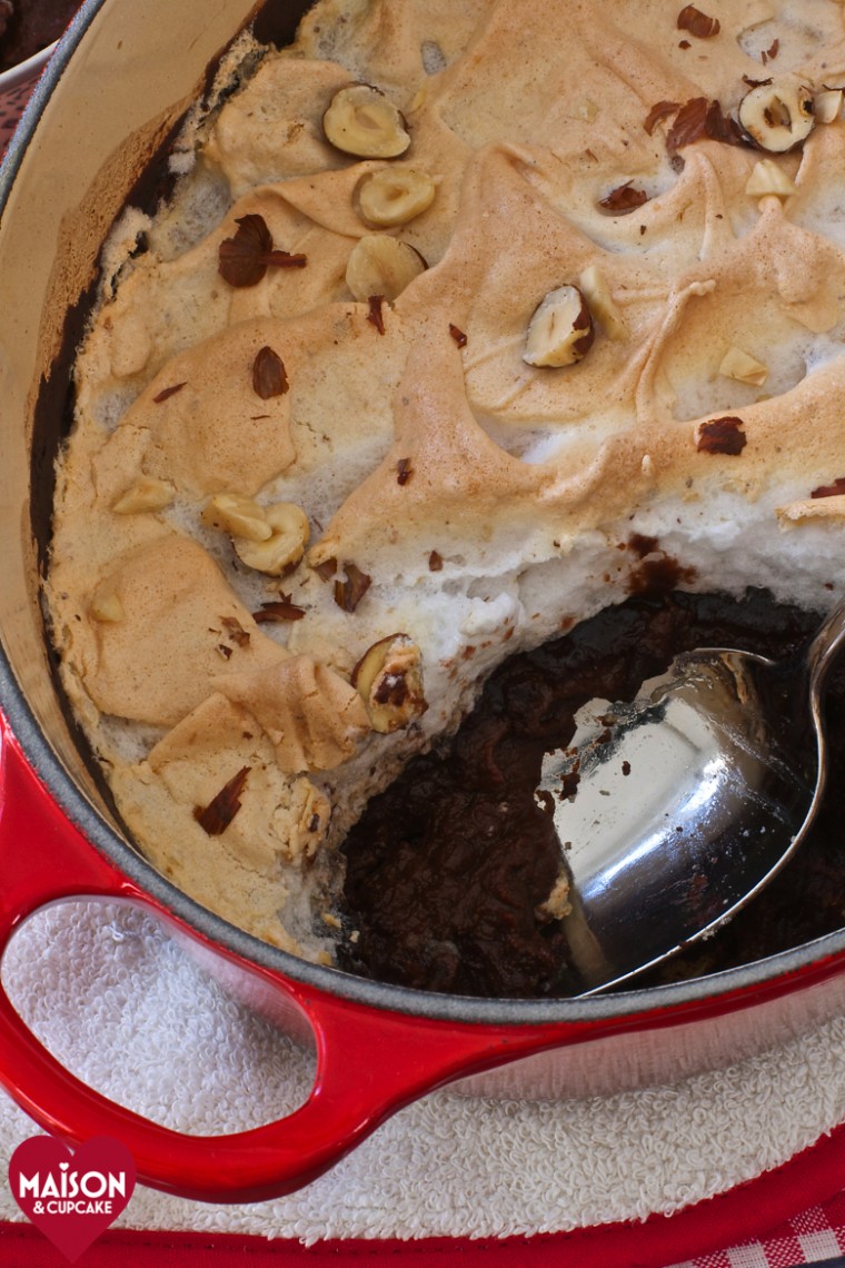 Nutella Semolina Meringue Pudding, seen from above, in an oval shaped red casserole dish, on a red gingham cloth. 