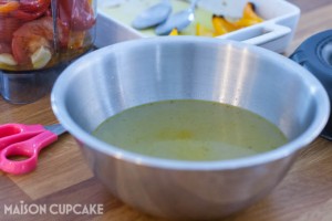 Vegetable stock, strained from simmered vegetables, in a stainless steel bowl.