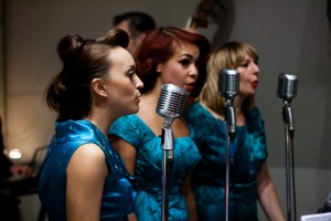 Girl singing trio in blue satin dresses with vintage microphones