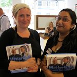 Two ladies holding Masterchef books with Gregg Wallace behind them