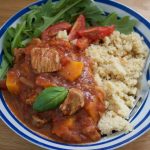 Turkey Thigh Tagine stew served in a blue stripey bowl alongside rocket and cous cous - landscape