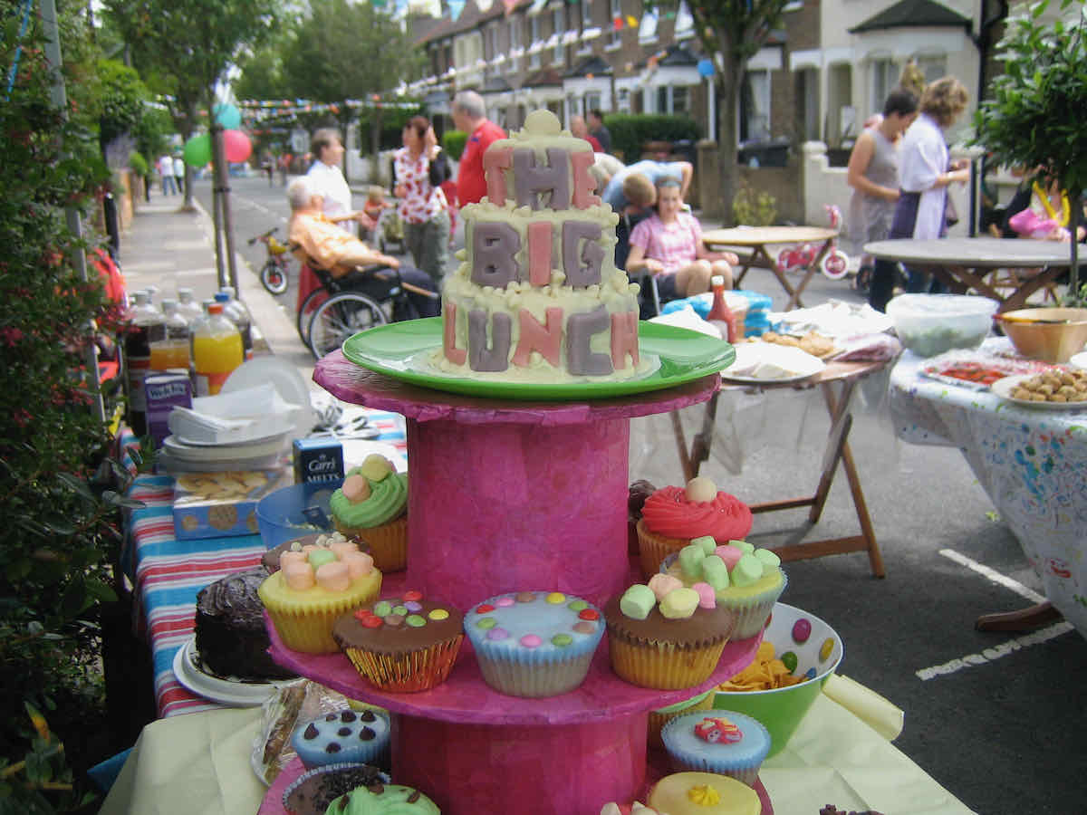 A street party scene with bunting and a cake saying The Big Lunch in foreground on a pink cake stand. Photo copyright Sarah Trivuncic 2009, all rights reserved, no reproduction without permission.