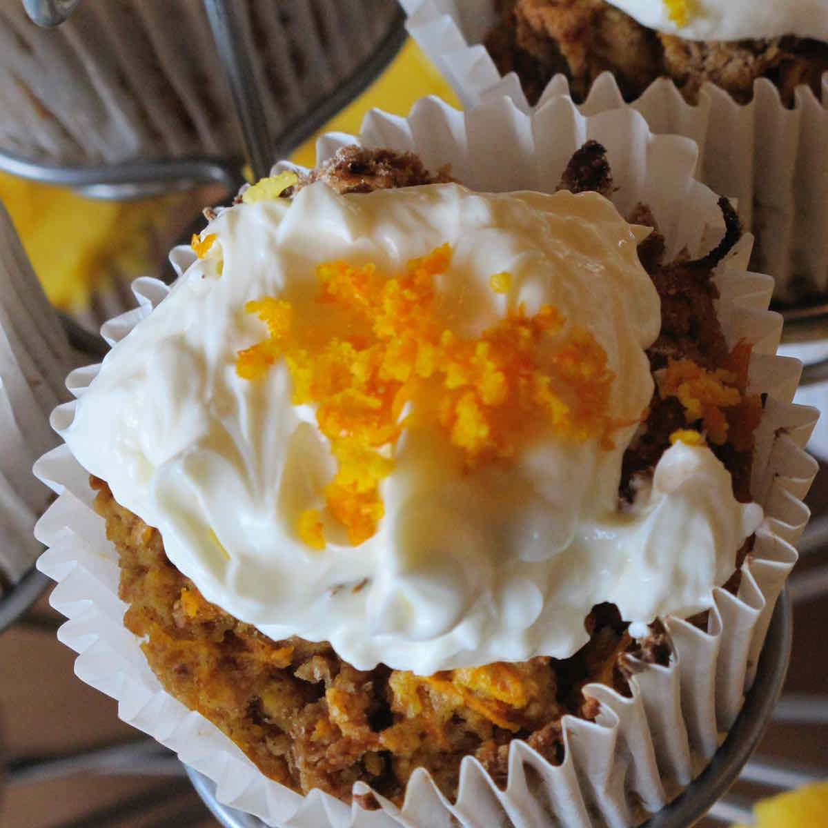 Carrot cake muffin topped with white cream cheese icing and grated carrot.