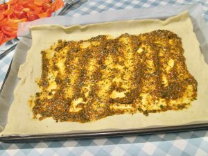 Rectangle of raw puff pastry upon a baking sheet and parchment paper, spread with sun-dried tomato paste but leaving a 3-4cm border to be brushed with milk.