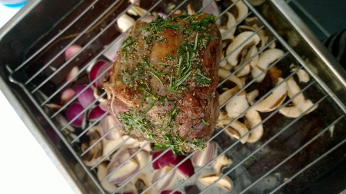 Roast Lamb on a wire rack with mushrooms and red onions