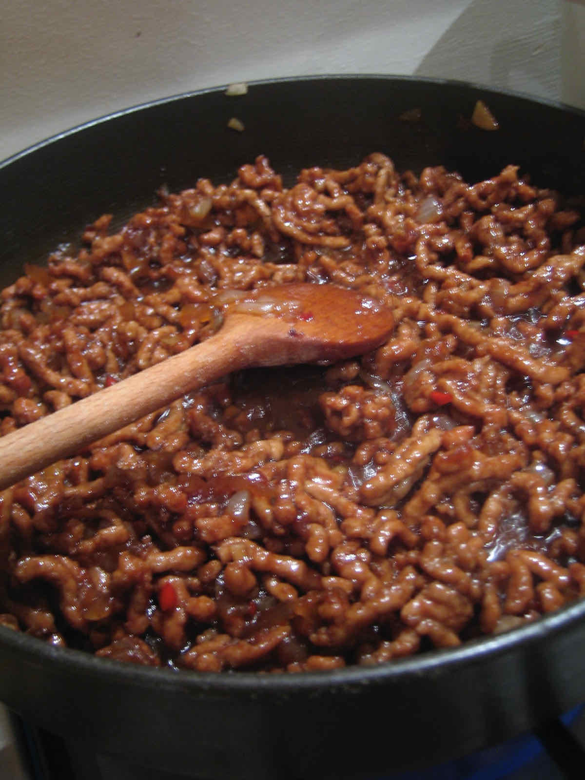 Minced pork fried in a dark brown spicy sauce in a pan