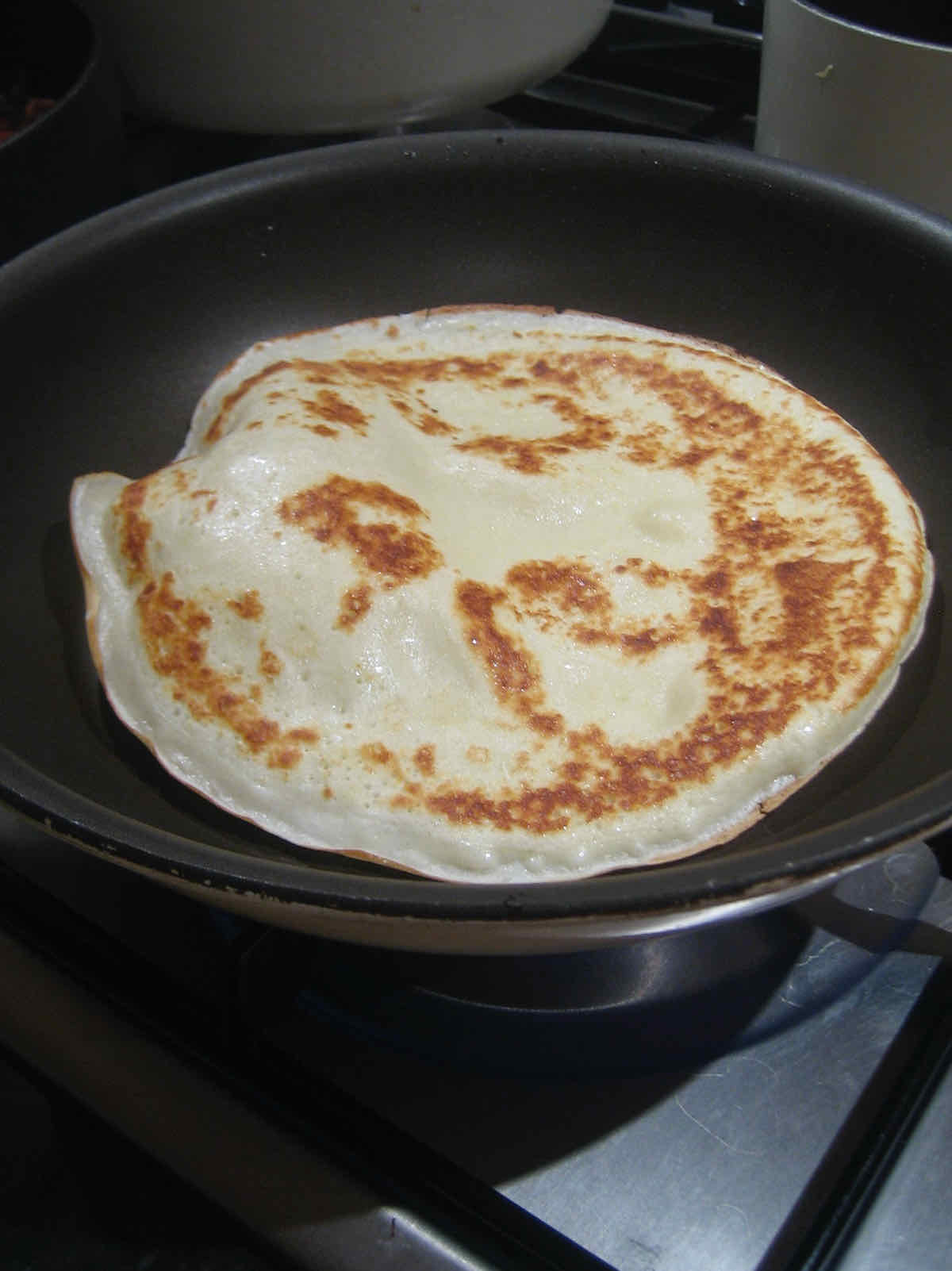 A golden pancake in a frying pan