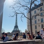 Parisian outdoor restaurant terrace with Eiffel Tower behind.