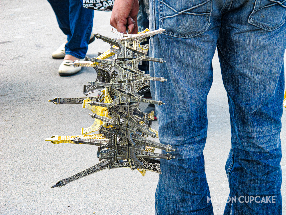 Souvenir seller's hand clutching bundle of metal Eiffel Towers.