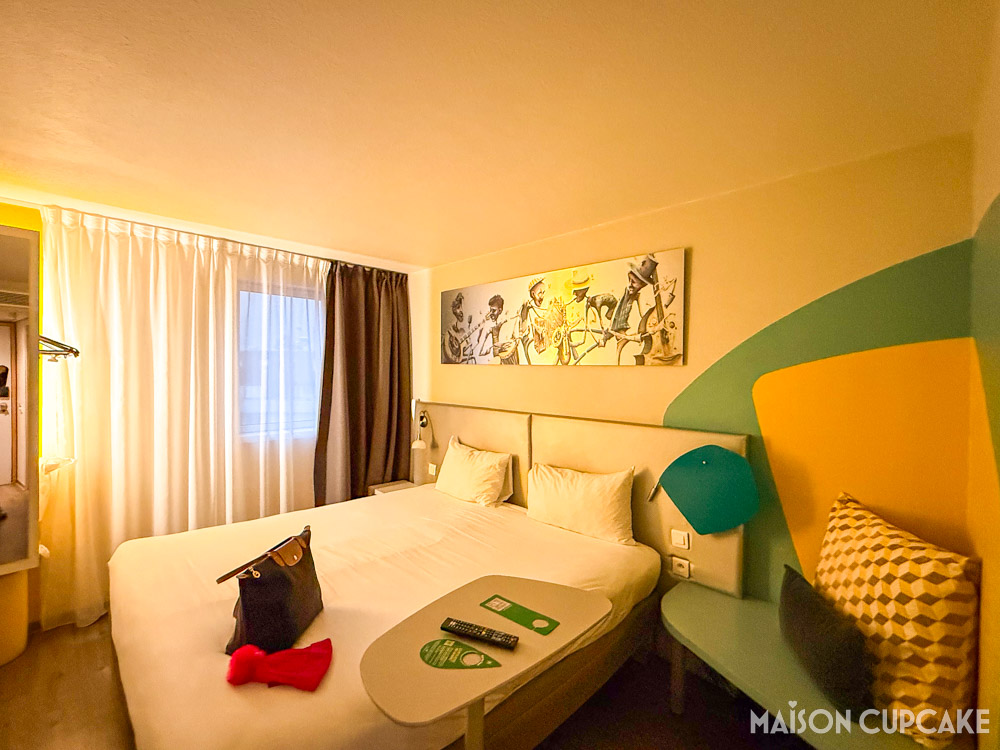 Double room at Ibis Styles Paris Bercy, with side table and colourful cushioned corner seat.