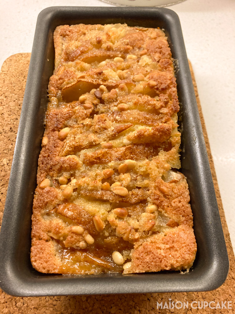 Overhead view of apple and pine nut pound cake baked in loaf tin with golden crust - with cork mat underneath