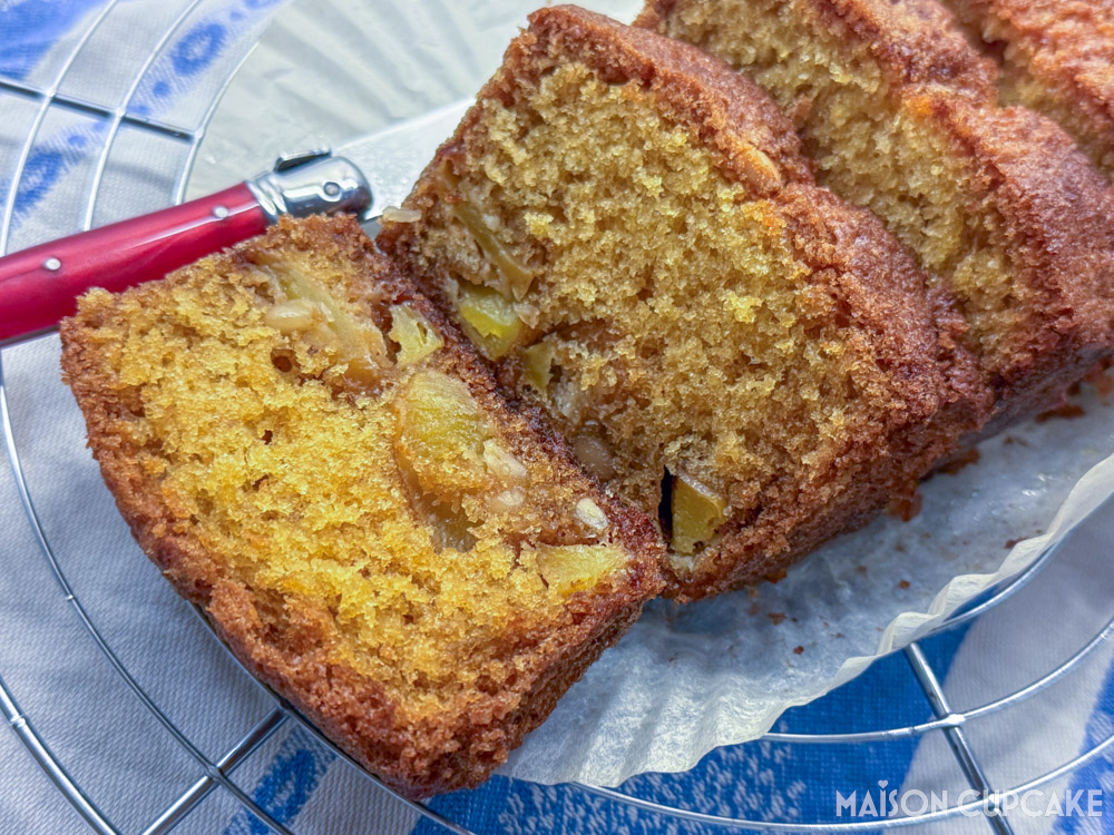 Thick golden slices of apple and pine nut pound cake on paper liner on cooling tray with French pink Laguiole knife.