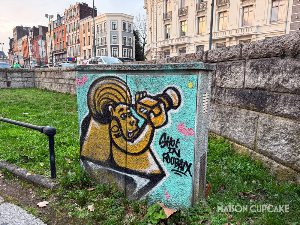 Street art in Roubaix: a cartoon character with camera is captioned "Shot in Roubaix"
