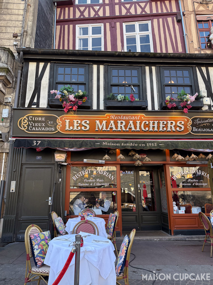 Timber medieval exterior of Les Maraichers restaurant with outdoor tables in Rouen, France.