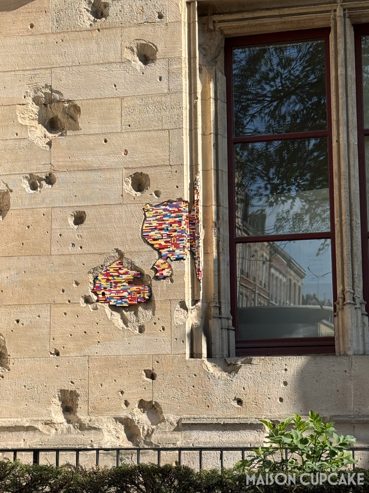 Bullet marks in Rouen's Palais de Justice filled with colourful Lego pieces.