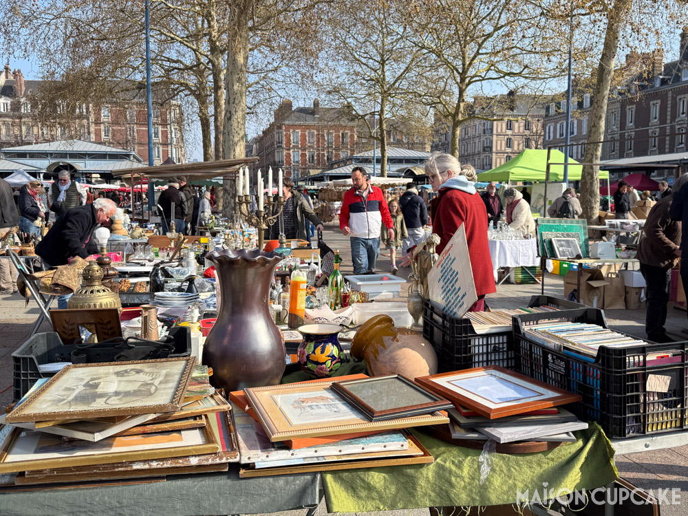 French flea market brocante stall in Rouen on a sunny spring day, picture frames, metal urn and candleabra amongst goods for sale.