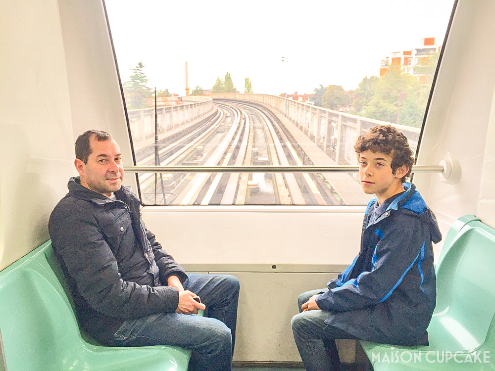 Father and Son riding Lille Metro at front of driverless carriage with view of rails